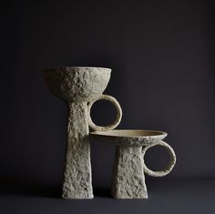 two stone sculptures sitting next to each other on a black background, one is shaped like a toilet and the other is made from concrete