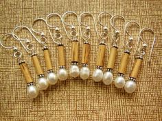 six pairs of earrings with wooden beads and silver wire on a brown fabric background,