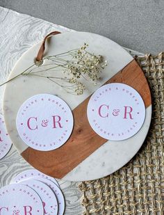 three round stickers with initials on them sitting on a plate