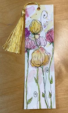 a bookmark with flowers painted on it and a tassel hanging from the end