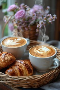 two cups of cappuccino and croissants sit on a tray