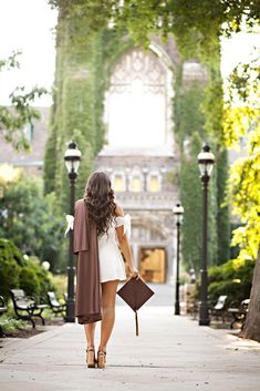 a woman walking down a sidewalk with an umbrella in her hand and holding a book