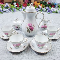 a table topped with lots of white cups and saucers covered in pink flowers next to each other