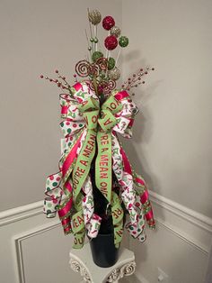 a christmas tree decorated with candy canes and ribbons in a vase on the wall