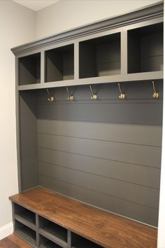 a wooden bench sitting in the middle of a room next to a wall with hooks on it