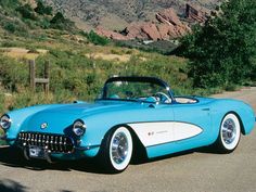 an old blue and white car parked on the side of the road