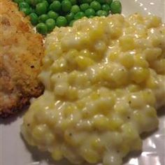 a white plate topped with mashed potatoes and green peas