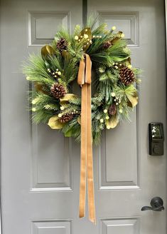 a wreath with pine cones and greenery hangs on the front door