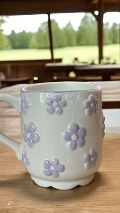 a white coffee cup with purple flowers on it