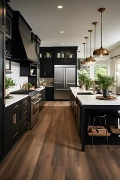 a large kitchen with black cabinets and white counter tops, wood flooring and pendant lights