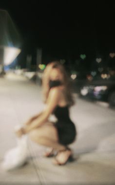 a blurry photo of a woman sitting on the sidewalk