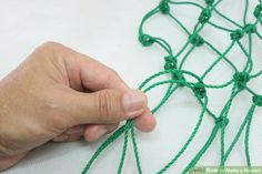 a hand is stitching green thread on a piece of cloth