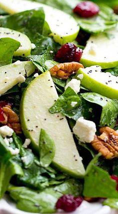 spinach salad with apples, cranberries and pecans in a white bowl