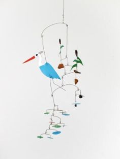 a wind chime hanging from the ceiling in front of a white wall with birds on it