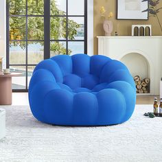 a large blue bean bag chair sitting on top of a white rug in front of a fireplace