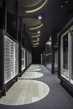 an empty hallway with multiple windows and circular lights on the ceiling is lit by recessed lighting