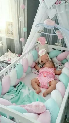 a baby laying in a crib with pink and blue decorations