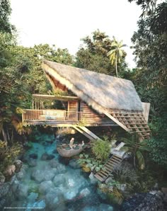 an aerial view of a house in the jungle with a river running through it and two people sitting on their rafts