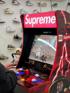 a person playing a video game in a room with shoes on the wall behind it