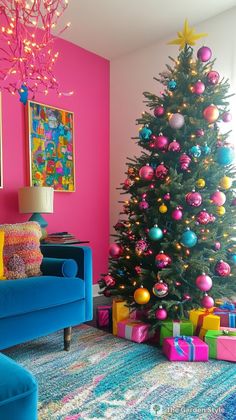 a brightly colored christmas tree in a living room with pink walls and blue couches