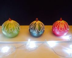 three ornaments with lights on them sitting on a table