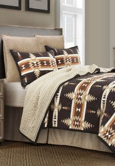 a bed in a bedroom with a brown and white blanket on top of the bed