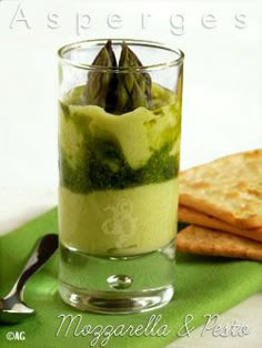 a glass filled with green liquid next to crackers