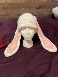 a white knitted hat with pink ears on top of a mannequin head