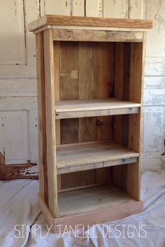 a wooden shelf sitting on top of a white sheeted floor next to a wall