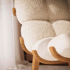 a chair with three pillows on it in front of a window