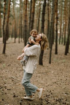 a woman holding a child in the woods