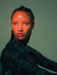 a woman with braids wearing a black and green shirt is posing for the camera