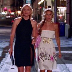 two women walking down the street at night in dresses with high slits on them