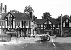 an old black and white photo of a street with cars parked in front of buildings