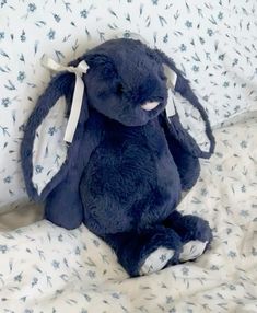 a blue stuffed animal sitting on top of a bed covered in white and blue sheets