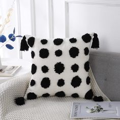 a black and white polka dot pillow sitting on top of a couch next to a book