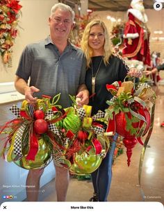 a man and woman standing next to each other holding christmas decorations