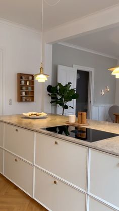 a kitchen with white cabinets and an island in the middle is lit by two pendant lights