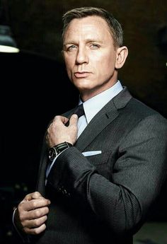 a man in a suit and tie is posing for a photo with his hands on his chest