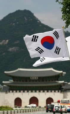 a flag flying in front of a building with mountains in the background