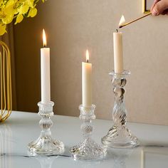 a person lighting candles on a table with yellow flowers in the background