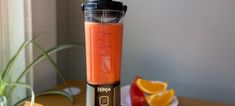 a blender filled with oranges on top of a wooden table