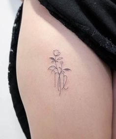 a small flower tattoo on the back of a woman's thigh