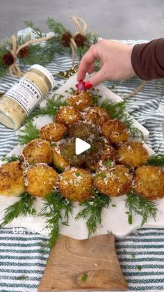 a person is decorating some food on a platter with pine cones and sprigs