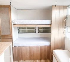 a bunk bed in the corner of a room with wood flooring and white walls