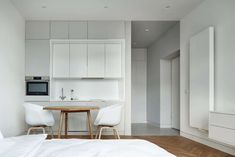 a white kitchen and dining area in a small apartment with wood flooring on the side