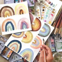 someone is painting rainbows with watercolors on paper