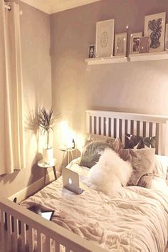 a laptop computer sitting on top of a bed in a room with white walls and pillows