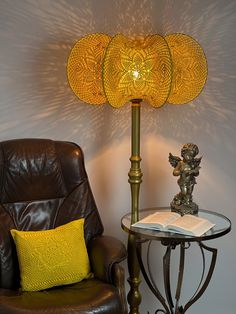 a lamp sitting on top of a table next to a brown chair and a book