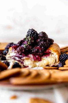 a piece of bread with berries on top is sitting on a wooden plate next to crackers